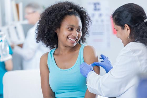 Doctor applying bandaid after a vaccine shot