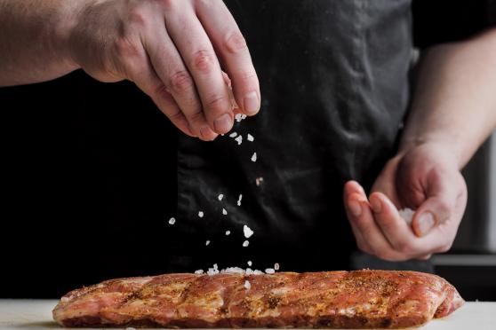 Photo: Hand sprinkling salt on raw steak