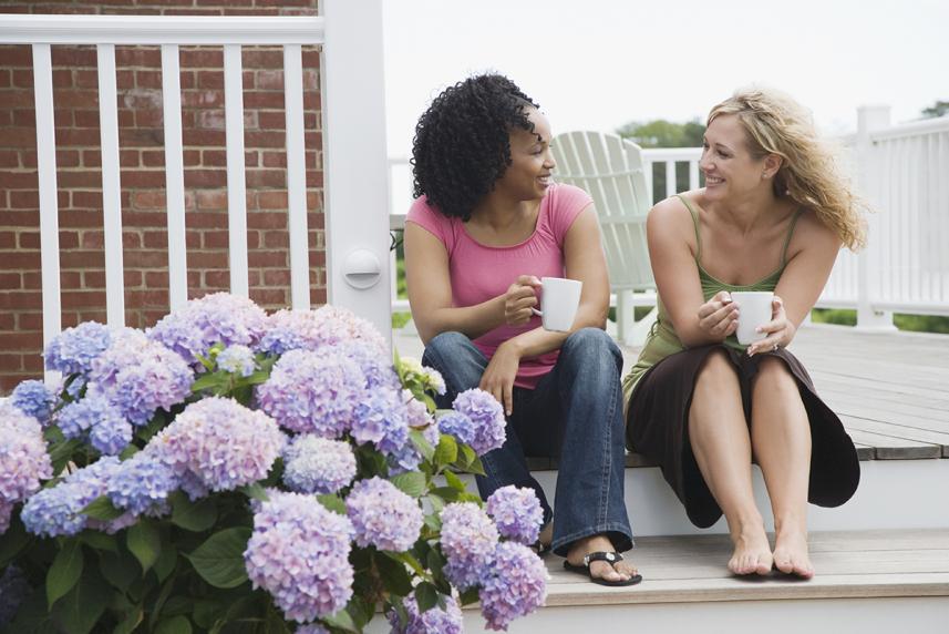 Woman on the porch with cups of coffee talking to each other