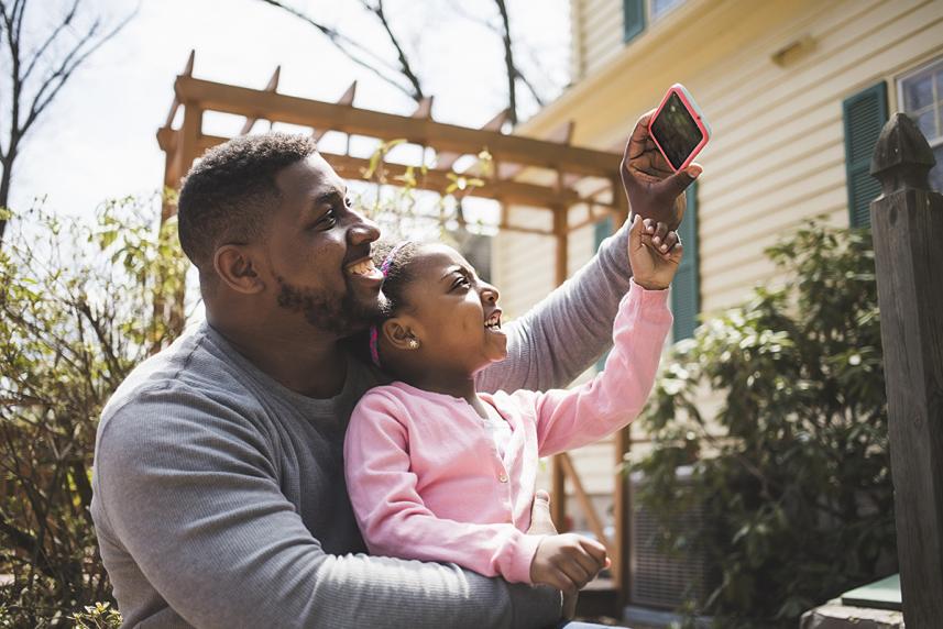 Father and daughter taking a selfie outside.